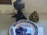 une assiette bleue et blanche posée sur une table, à côté d'une lampe