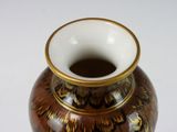 a brown and gold vase on a white surface