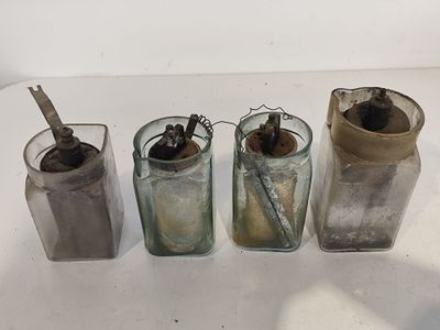 trois vieux bocaux en verre contenant une cuillère et une brosse à dents