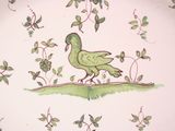 a plate with a bird painted on it on a table