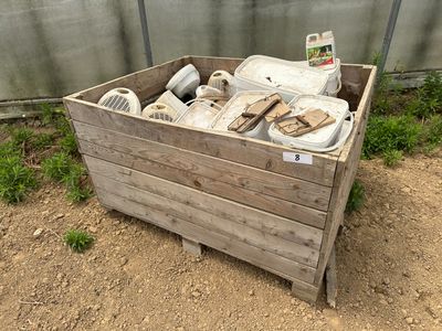 une caisse en bois remplie de déchets, posée par terre à l'extérieur