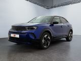 a blue car is parked in a large room with a white wall