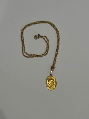 Gros plan sur un collier en or sur lequel se trouve une pièce de monnaie