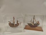 two miniature ships in a glass case on a table