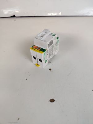 une petite boîte blanche avec une étiquette jaune et verte posée sur une surface blanche