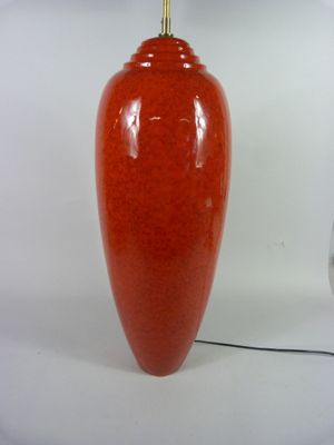 un vase rouge posé à côté d'une lampe