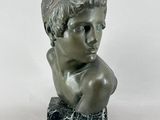 statue d'un jeune garçon dont la tête repose sur un bloc de marbre