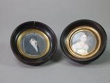 pair of miniature portraits of a woman and a man in a black and gold frame