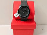 a black watch sitting on a red box with a price tag