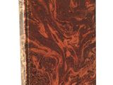 an old book with a marbled cover on a white surface