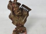 statue en bronze représentant une femme tenant un peigne, posée sur un socle en bois