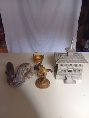 Des bougeoirs et des figurines sont posés sur une table devant un fond blanc.