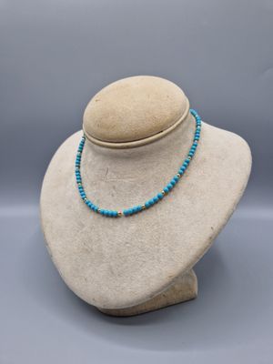 un mannequin blanc portant un collier de perles bleues
