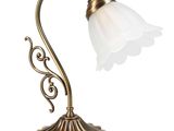 une lampe de table en laiton surmontée d'un abat-jour en verre blanc