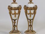 une paire de vases blancs et dorés posés sur des socles en marbre, sur fond blanc