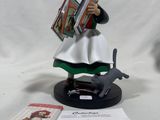 a figurine of a woman reading a book on a table