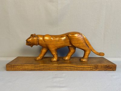 figurine en bois sculpté représentant un tigre, posée sur un socle en bois