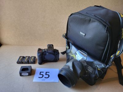 un sac à dos, un appareil photo, des piles et d'autres objets disposés sur une table