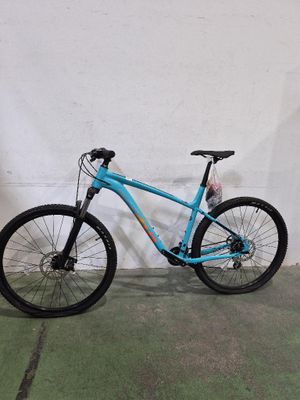 le vélo est bleu et la roue avant a des rayons noirs