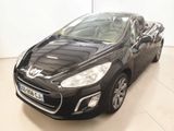 La voiture noire est garée dans une grande pièce au sol blanc.