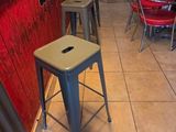 des tables et des tabourets dans un restaurant aux murs rouges et au sol carrelé