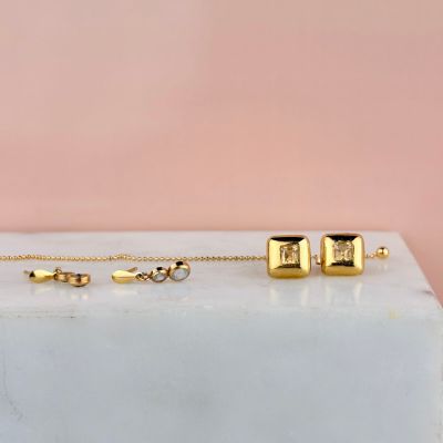 une paire de boucles d'oreilles en or et une chaîne en or posées sur un bloc de marbre
