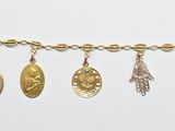 a close up of a gold bracelet with five charms on it