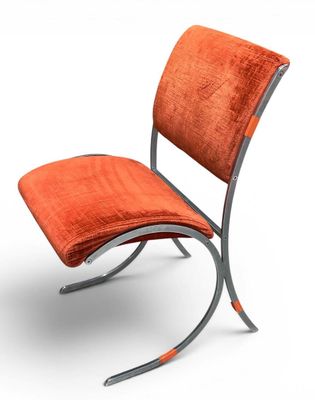 une chaise orange avec une structure métallique sur fond blanc