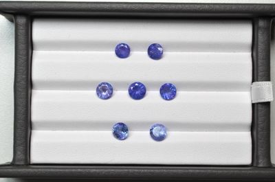 des saphirs bleus dans un écrin noir posé sur une surface blanche