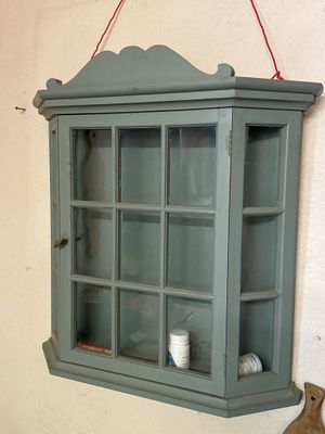 a shelf with a glass door and a vase on the wall