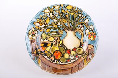 a plate with a vase of flowers and fruit on it