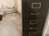 a black filing cabinet sitting in the corner of a room