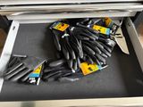 several pairs of black gloves are in a drawer with a pair of scissors