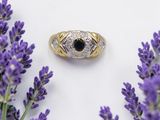 un gros plan d'une bague ornée d'une pierre noire entourée de fleurs violettes