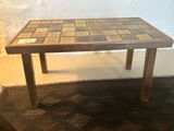 a small table with a tile top on a rug