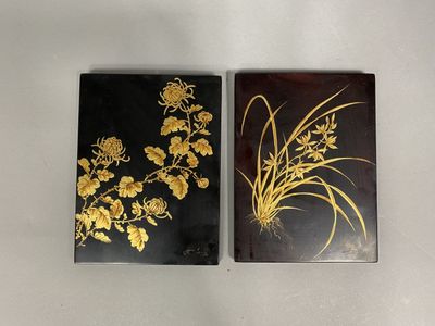 two black and gold coasters with flowers on them on a white surface