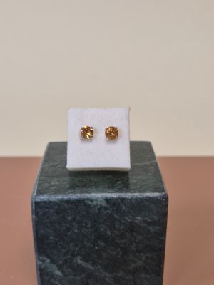 une paire de boucles d'oreilles en or posée sur un bloc de marbre