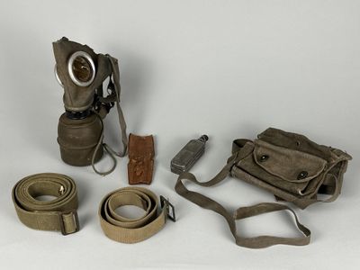 un masque à gaz, une ceinture et d'autres objets posés sur une surface blanche