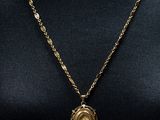 un collier en or avec un pendentif circulaire autour du cou d'un mannequin