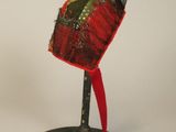 un chapeau rouge posé sur un support noir, orné d'un ruban rouge