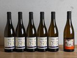 six bouteilles de vin sont alignées sur une table en bois