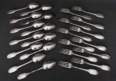 de nombreuses cuillères et fourchettes en argent posées sur une table noire