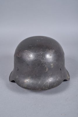 un vieux casque en acier posé sur une surface blanche, avec un fond gris