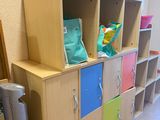 a wooden cabinet with colorful drawers and a trash can