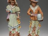 pair of porcelain figurines of children with hats and flowers