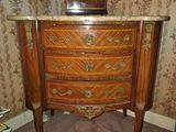une commode avec un plateau en marbre dans un coin de la pièce