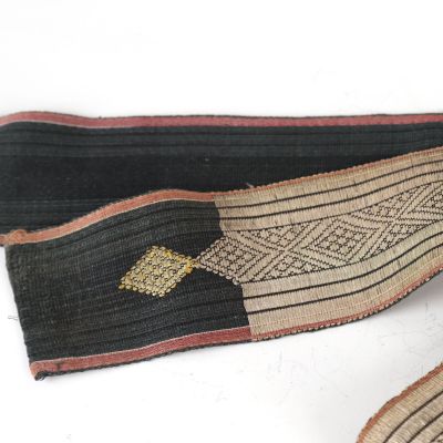 an image of a pair of black and tan belts with a gold arrow on them