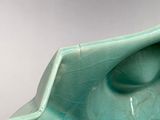 a green vase that has a bird on top of it