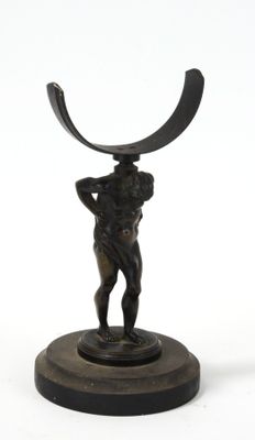 statue en bronze représentant un homme tenant un objet incurvé, posée sur un socle
