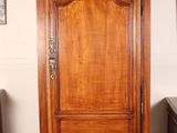 a tall wooden cabinet in a room with a mirror on the wall